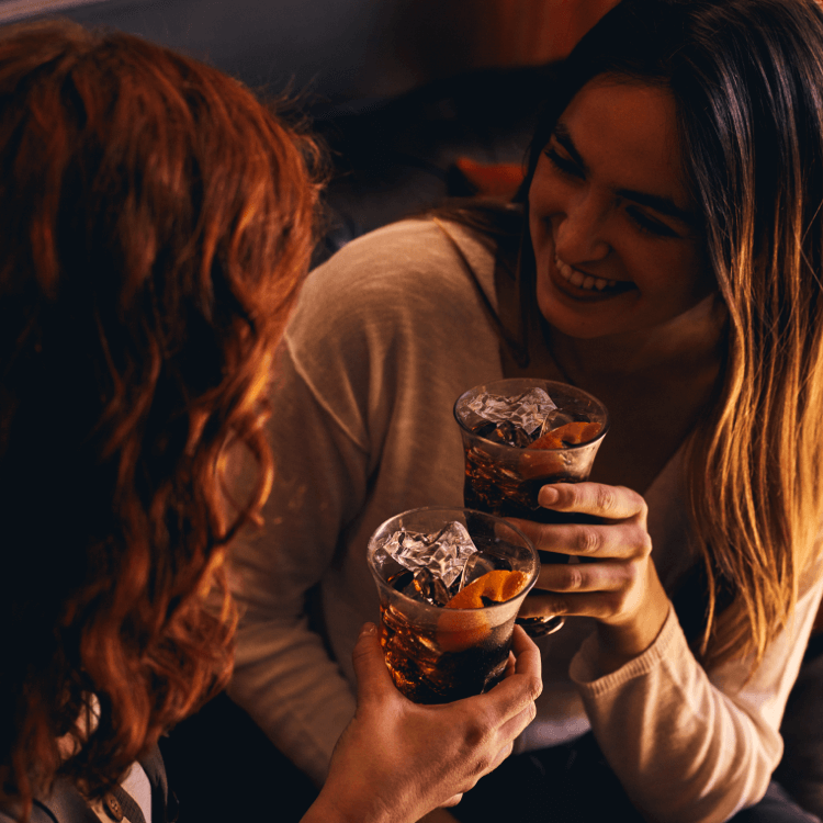 Two women each with a glass of Coca Cola and ice